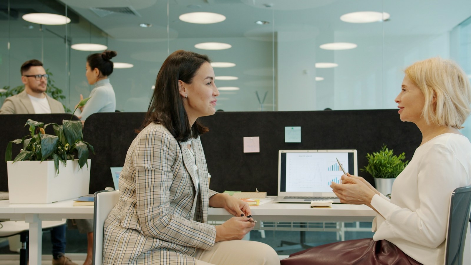 Two colleagues talking across a desk in a bright office